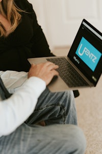 a man and woman sitting on the floor with a laptop