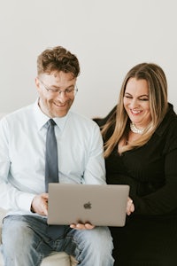 a man and woman sitting on a couch with a laptop